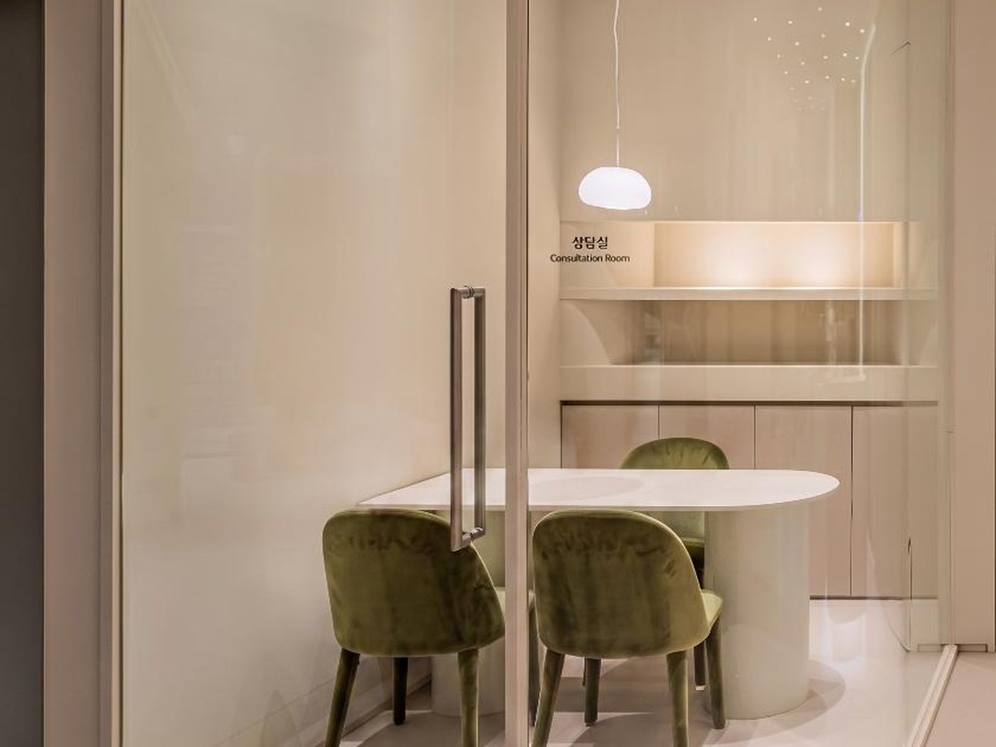 Concept image of a consultation room with a curved glass partition, oval table and green chairs